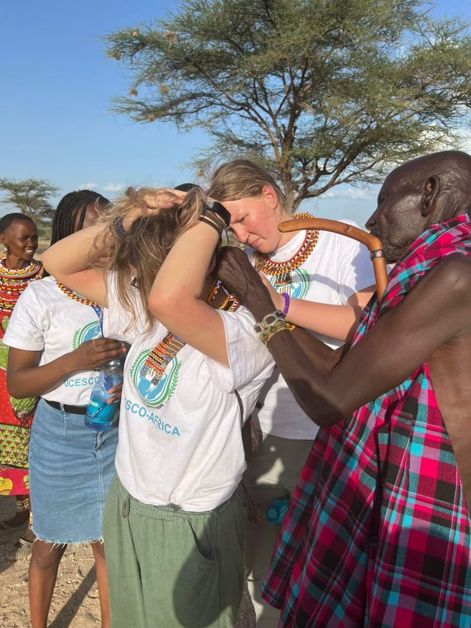 Maasai man putting beads on volunteer